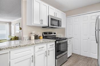The kitchen features granite counters, wood-look flooring and the laundry closet.